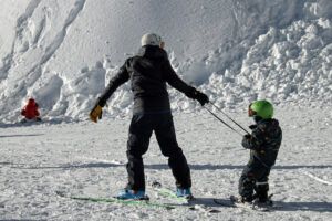 Adult teaching a beginner kid how to ski.