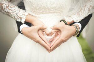 Bride and groom creating a heart with their hands in front of them.