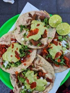 Four tacos with lime and salsa.
