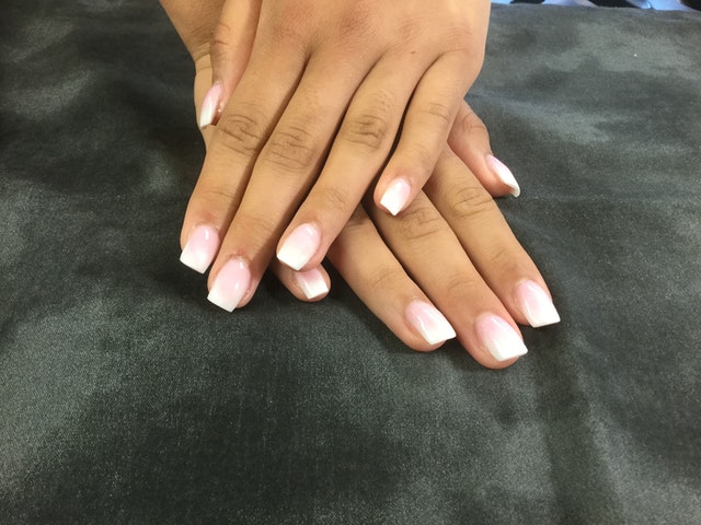 A woman showing both of her hands with a French manicure.