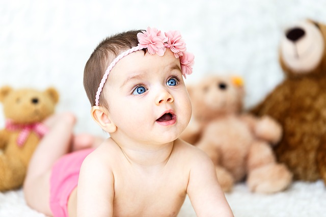 White baby girl with a pink bow on her head.