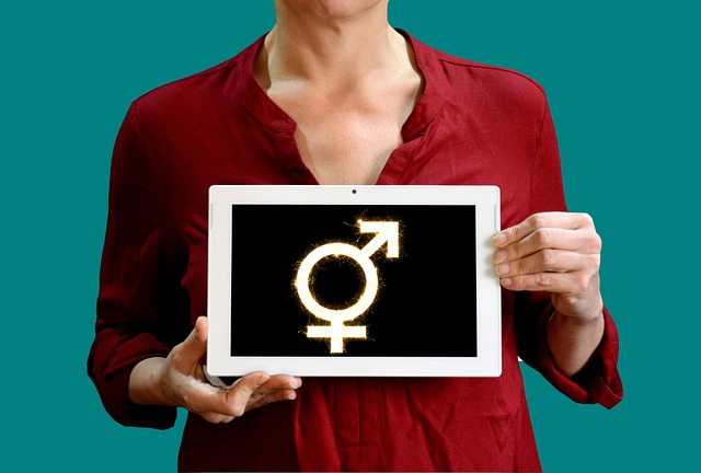 A woman dressed in red and holding a tablet with a masculine and feminine sign.