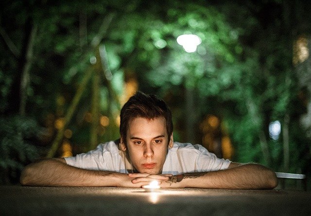 Young man looking at a candle and thinking.